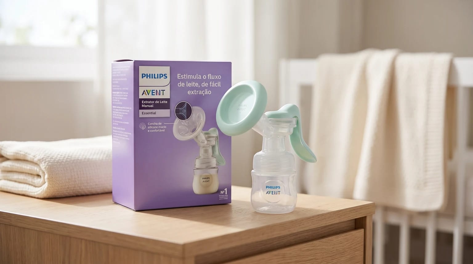 Bombinha manual Philips Avent ao lado da caixa roxa, sobre uma cômoda de madeira, com um berço branco e uma manta ao fundo.