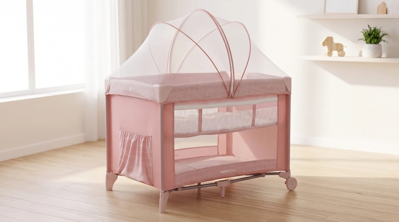 Berço portátil rosa, com laterais de tela, mosquiteiro e base na posição elevada, montado em um quarto claro.