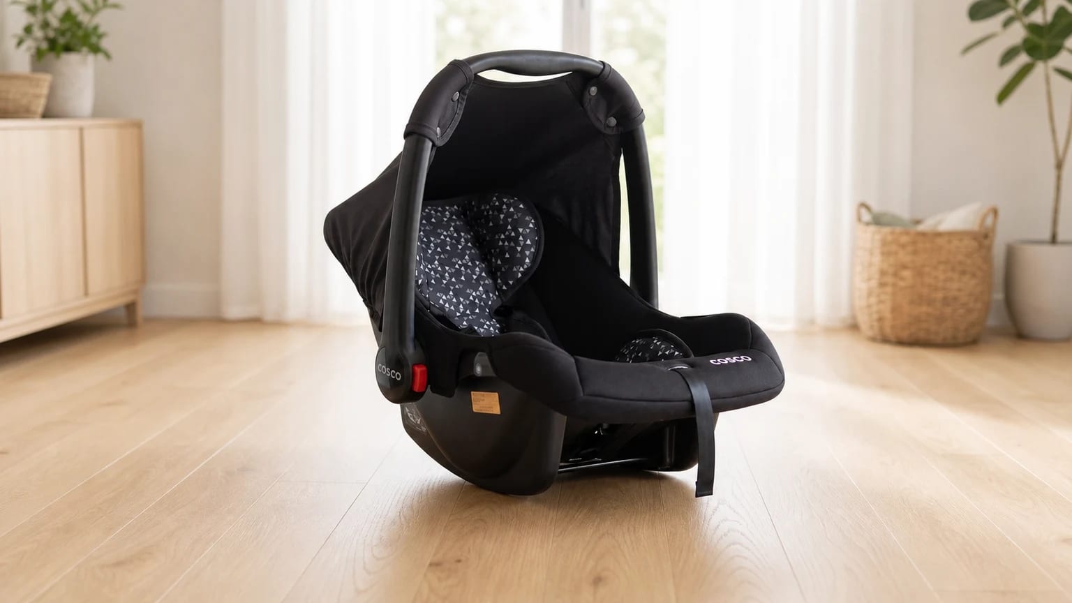 Bebê-conforto Cosco Wizz preto no chão de madeira clara de uma sala bem iluminada.