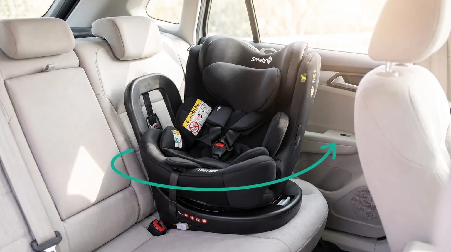 Cadeirinha Safety 1st i-NXT 360° preta instalada no banco traseiro, com uma seta turquesa indicando o giro.