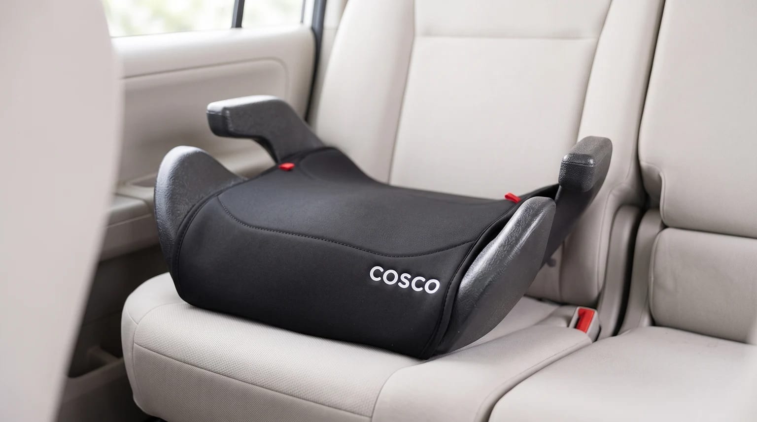 Assento de elevação Cosco Clippy sem encosto, preto, no banco traseiro de um carro com estofado claro.
