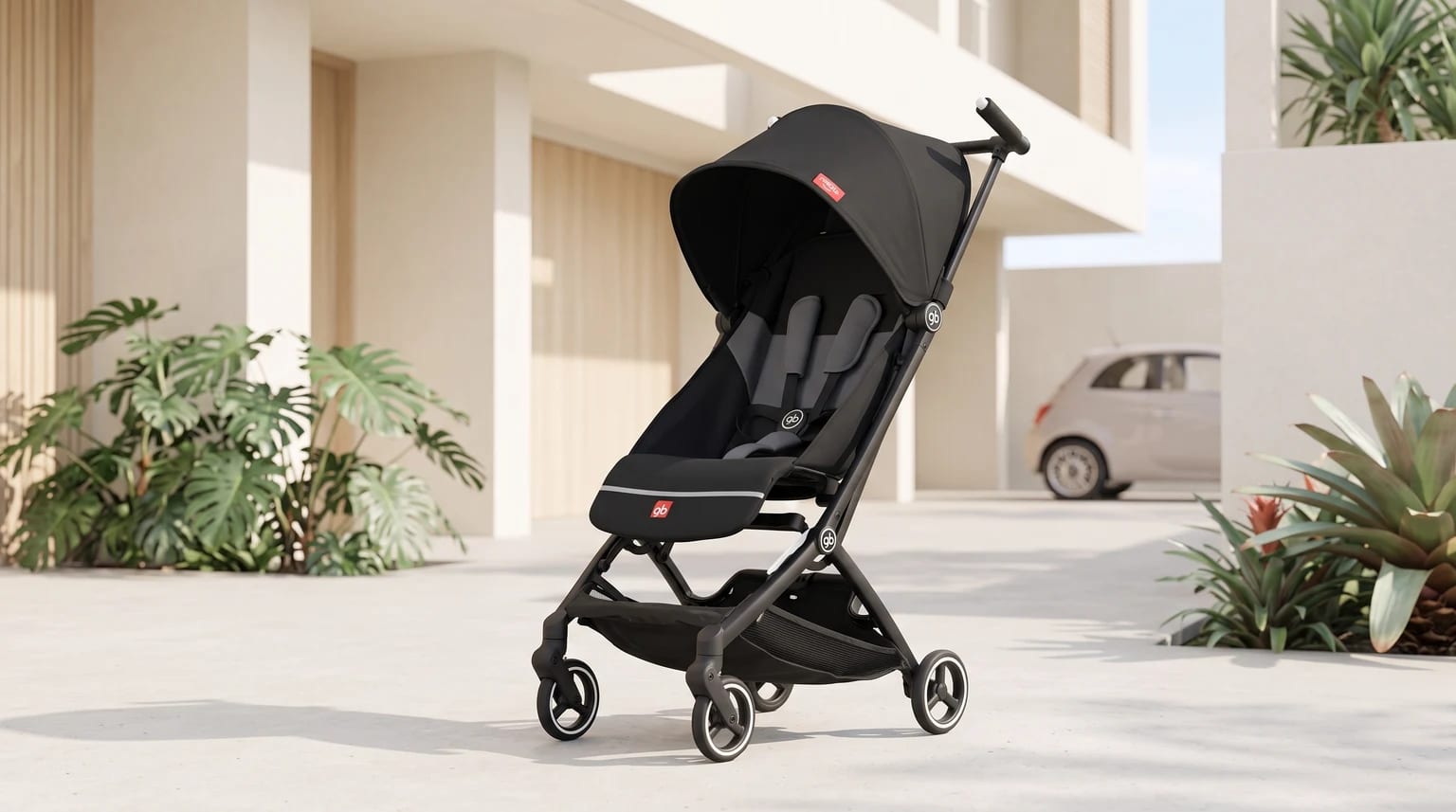 Carrinho de bebê compacto gb Pockit+ All-City preto na entrada ensolarada de um condomínio, com plantas e um carro ao fundo.