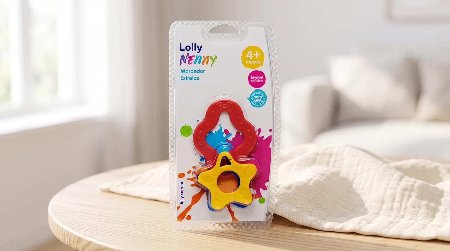 Embalagem do mordedor Lolly Nenny Estrelas nas cores vermelha, amarela e azul, sobre uma mesa de madeira em um ambiente claro.