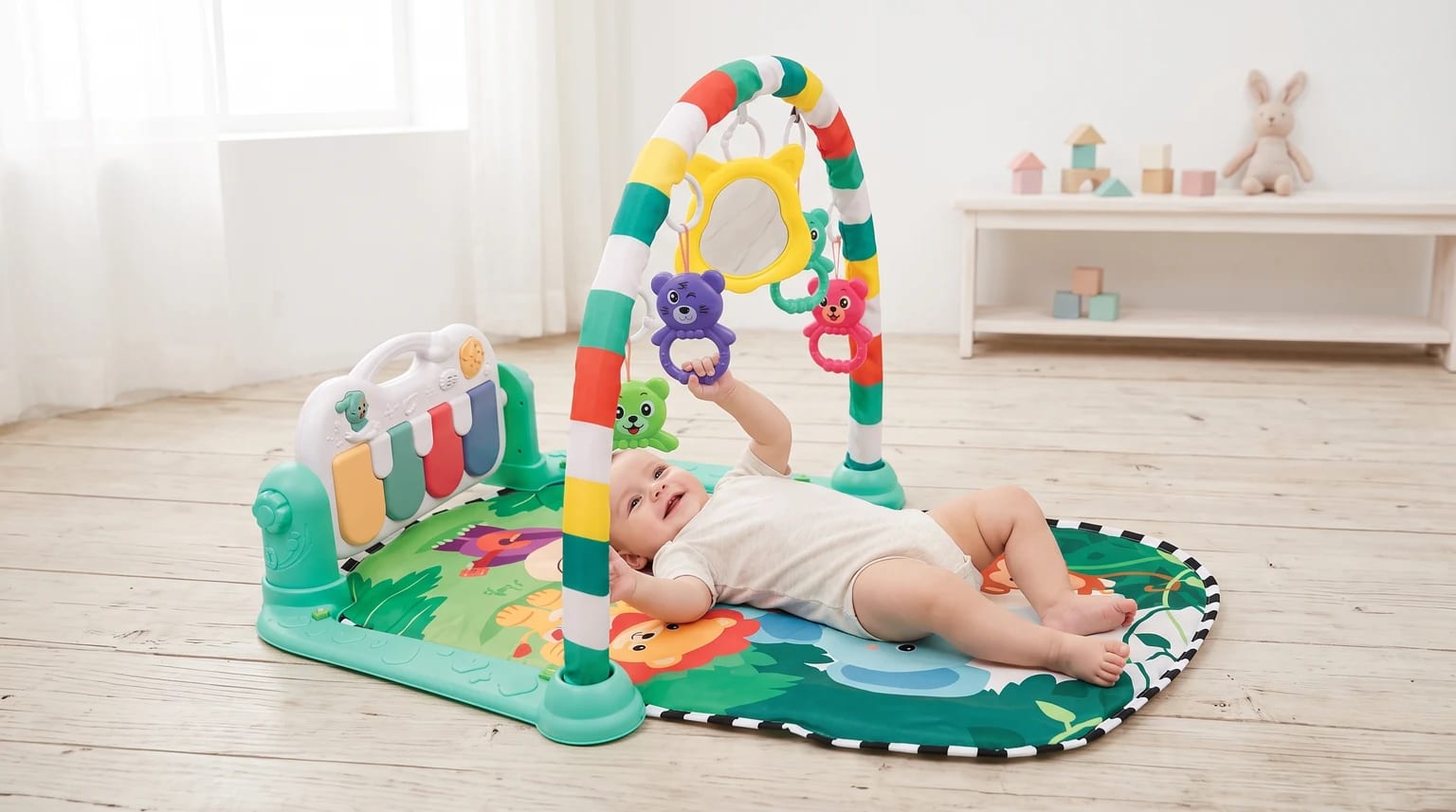 Bebê deitado no Buba Safari, estendendo a mão para um brinquedo pendente no arco colorido, com o piano ao lado.
