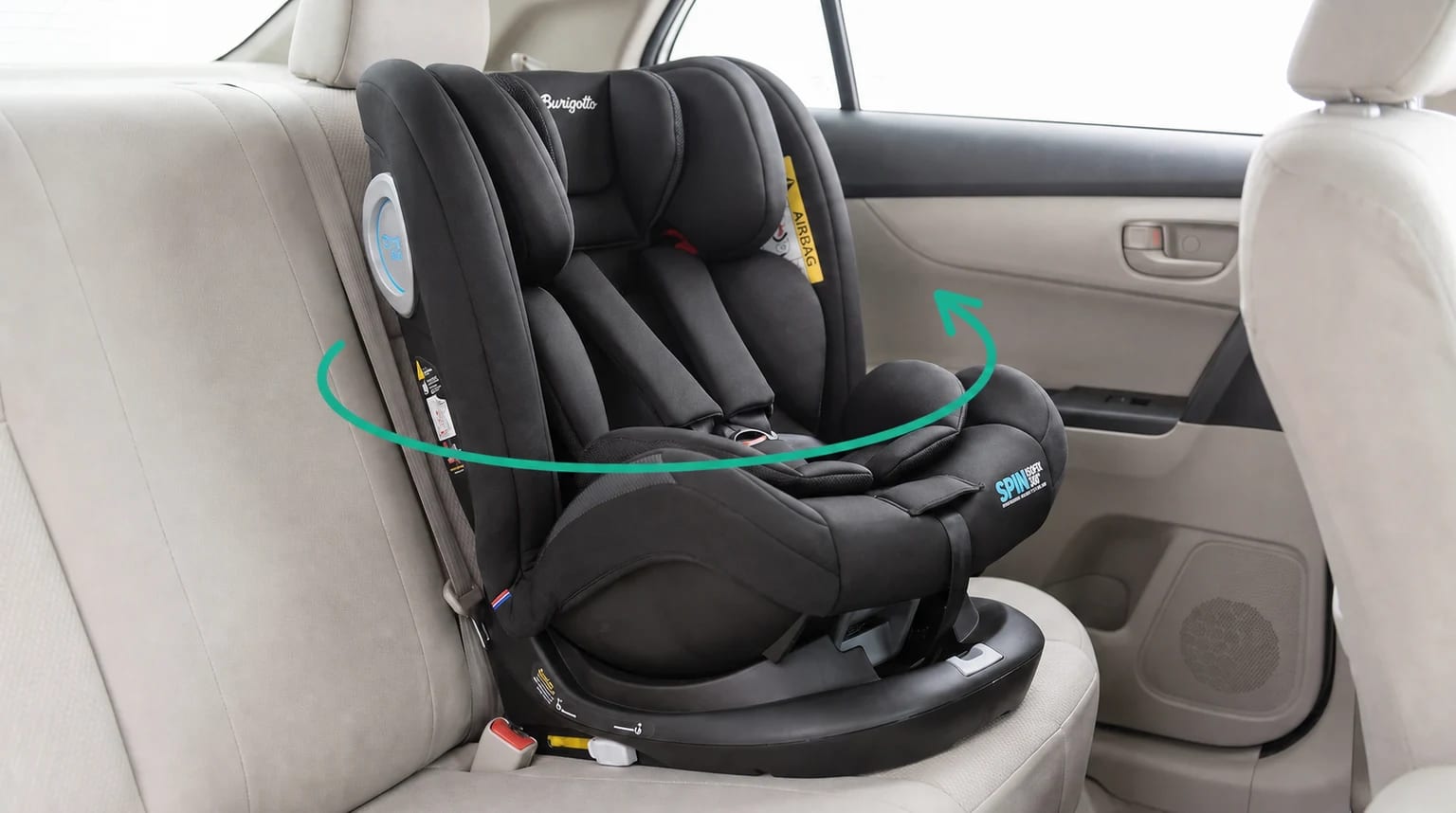 Cadeirinha Burigotto Spin ISOFIX 360° preta instalada no banco traseiro, com uma seta turquesa indicando o giro.