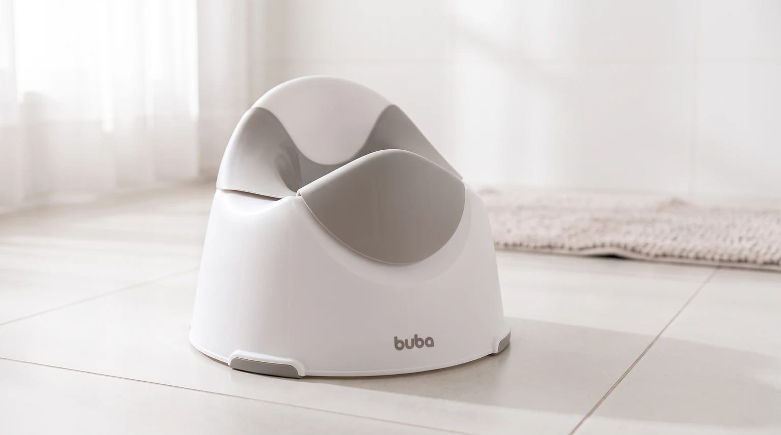 Troninho infantil branco e cinza da Buba sobre o piso de um banheiro claro, com um tapete ao fundo.