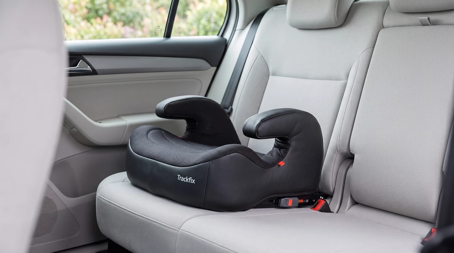Assento de elevação Safety 1st TrackFix sem encosto, preto, no banco traseiro de um carro com estofado claro.