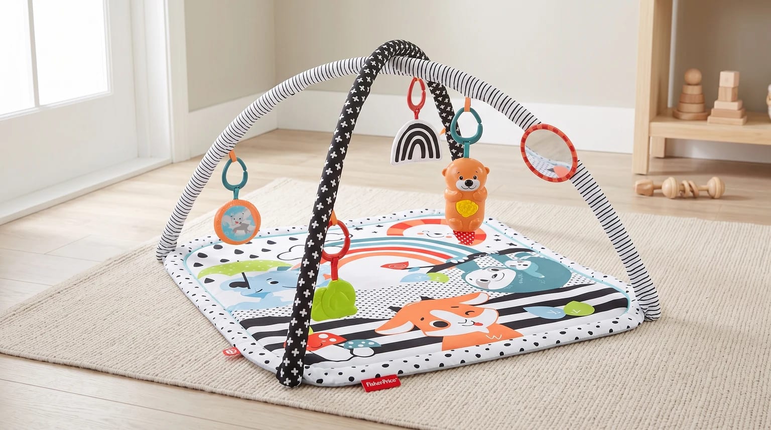 Fisher-Price 3 em 1 montado sobre um tapete claro, com arcos em preto e branco, brinquedos pendentes e espelho.