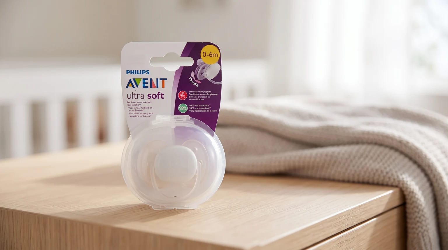 Embalagem da Philips Avent Ultra Soft com estojo transparente, sobre um móvel de madeira em um quarto de bebê.